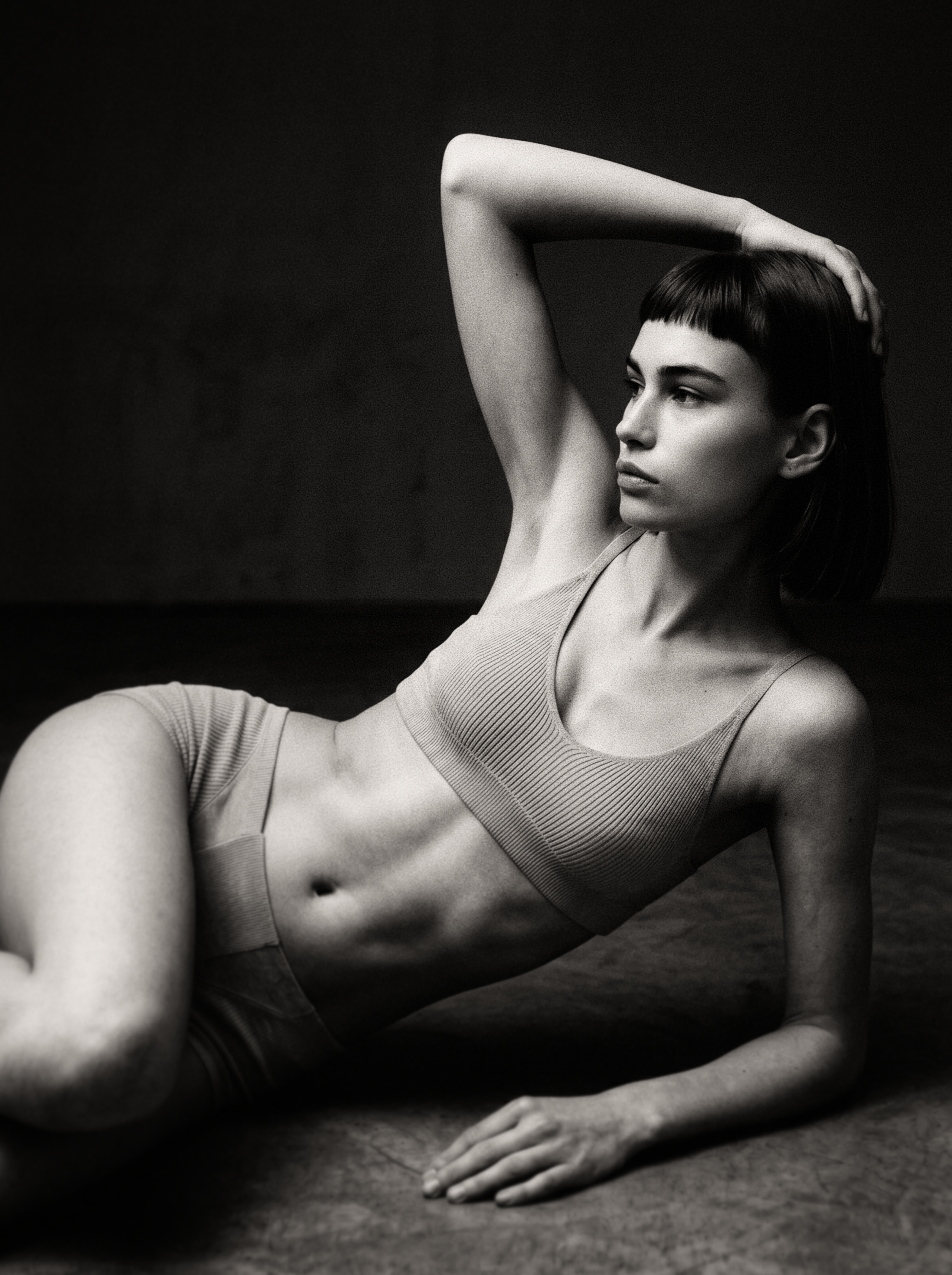 A reclining figure in fitted knit, side-lit