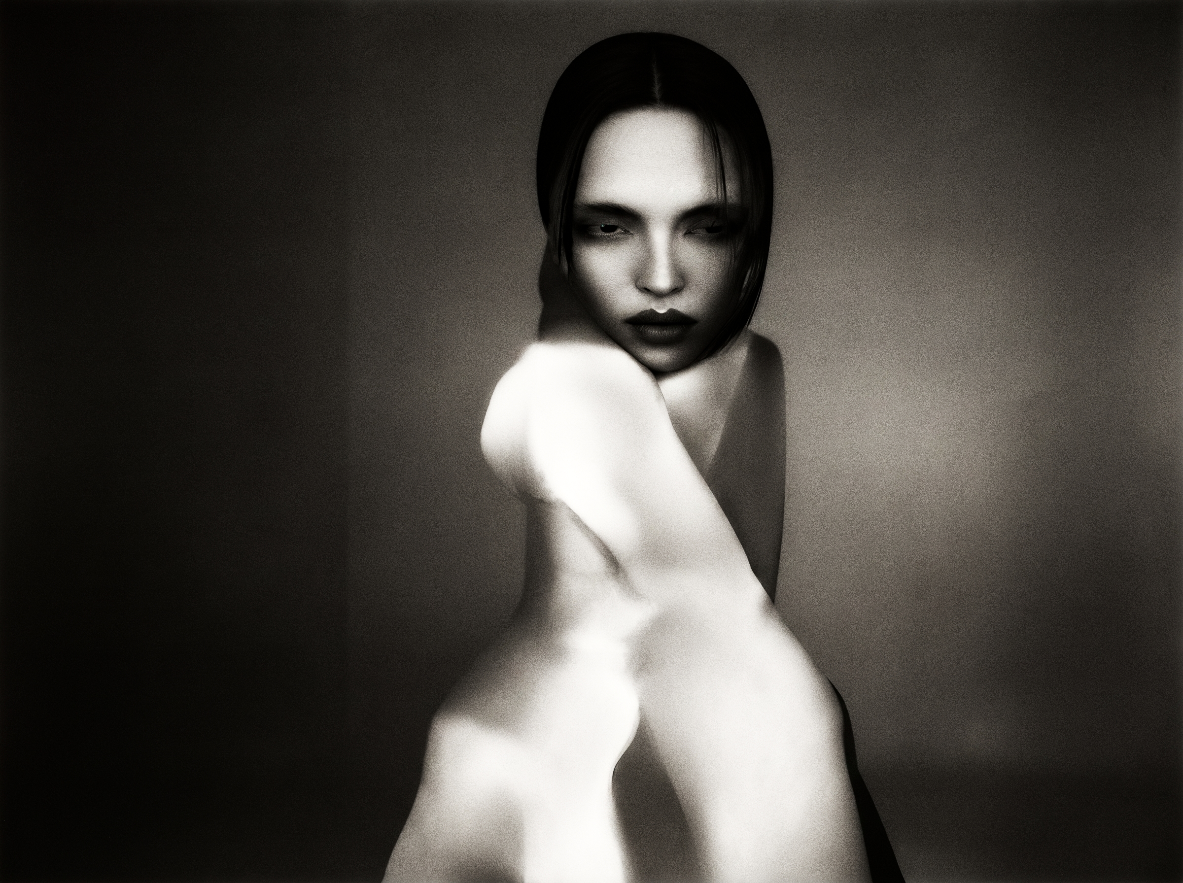 Black-and-white portrait, a dark-bobbed figure with a luminous bare limb crossing the frame in soft focus.