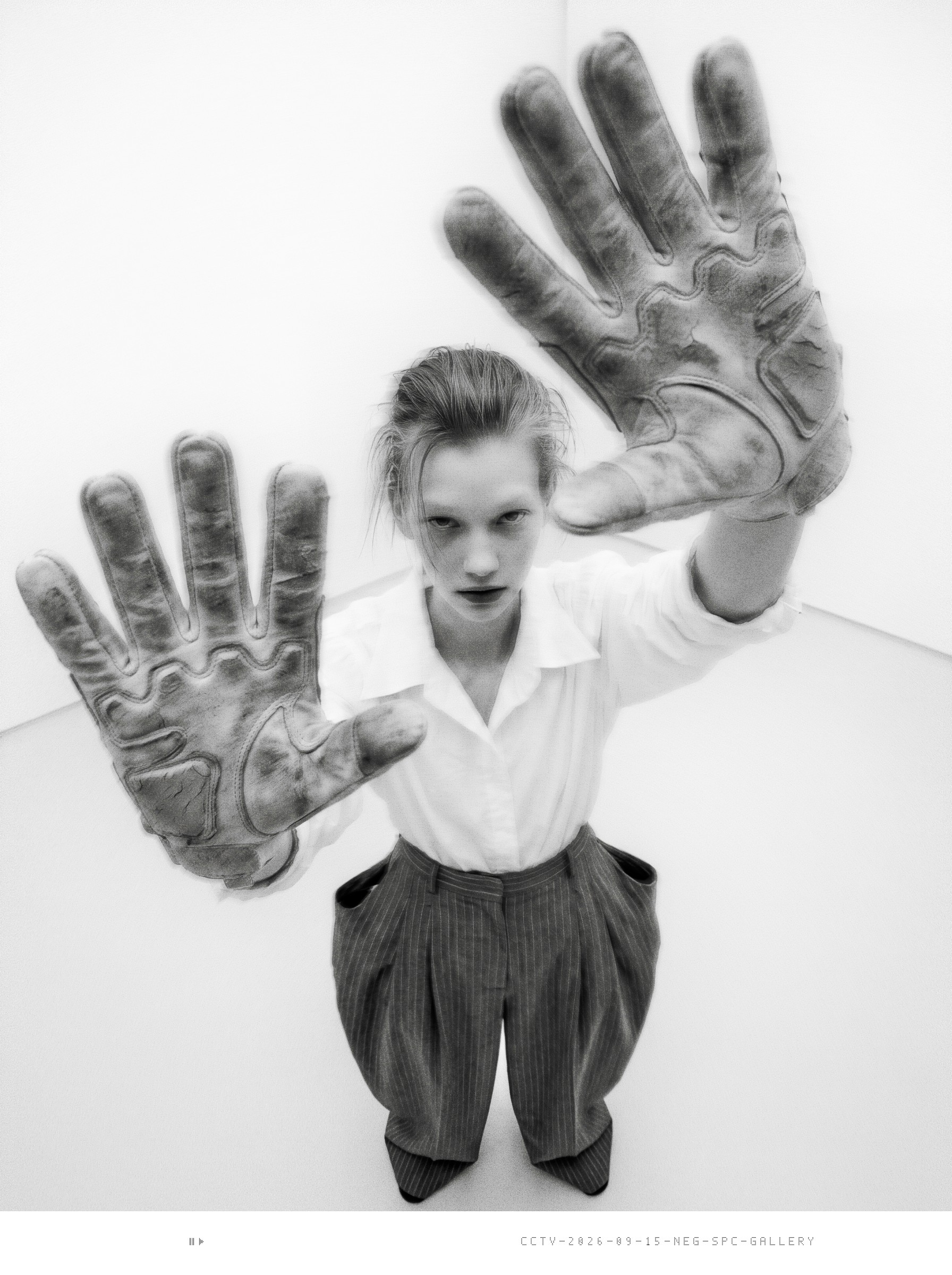 Security still: intern holds a large dirty work glove toward the lens; the other glove reads NEG SPC.