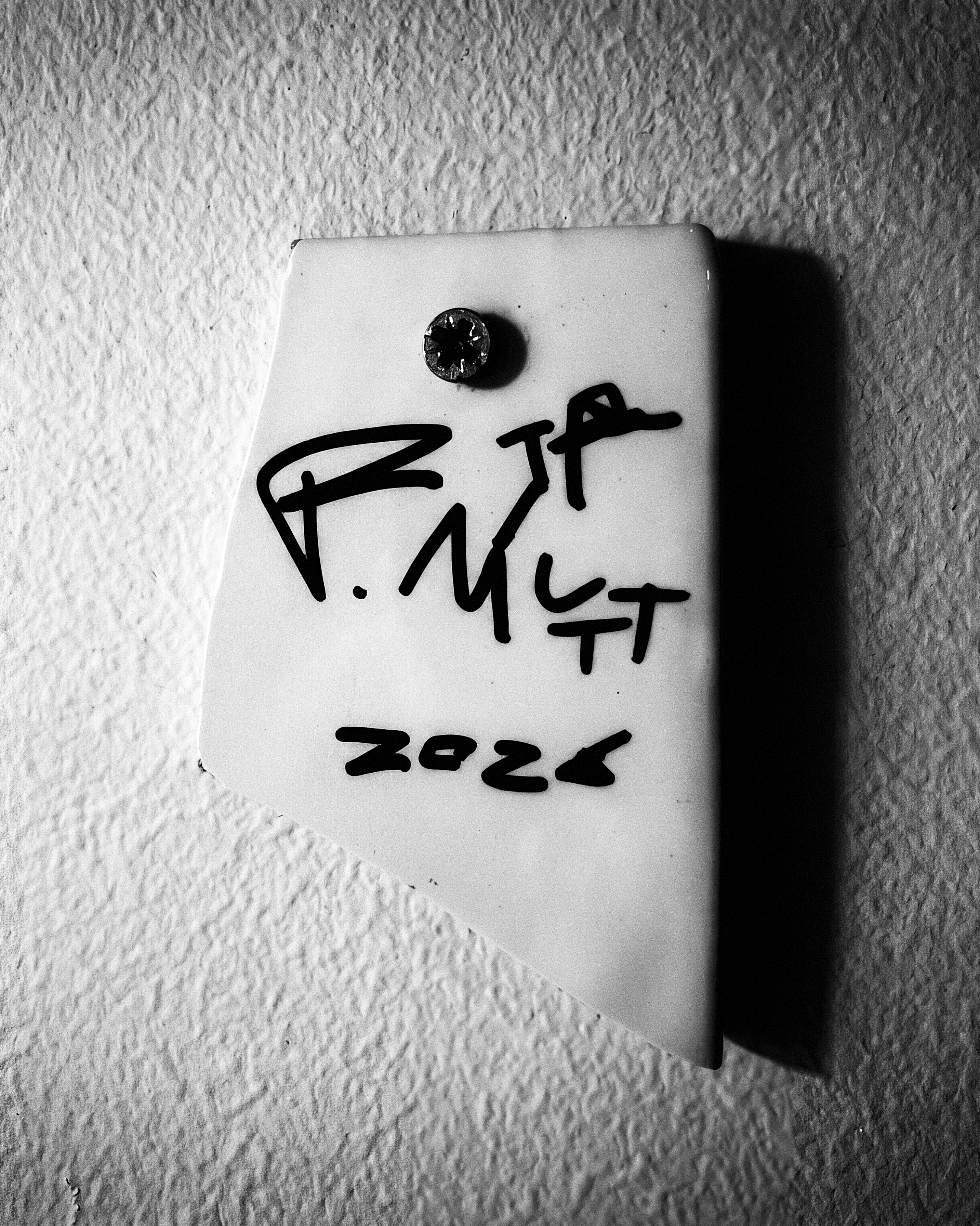 White wall plaque, handwritten R. MUTT 2026, fixed with one screw.