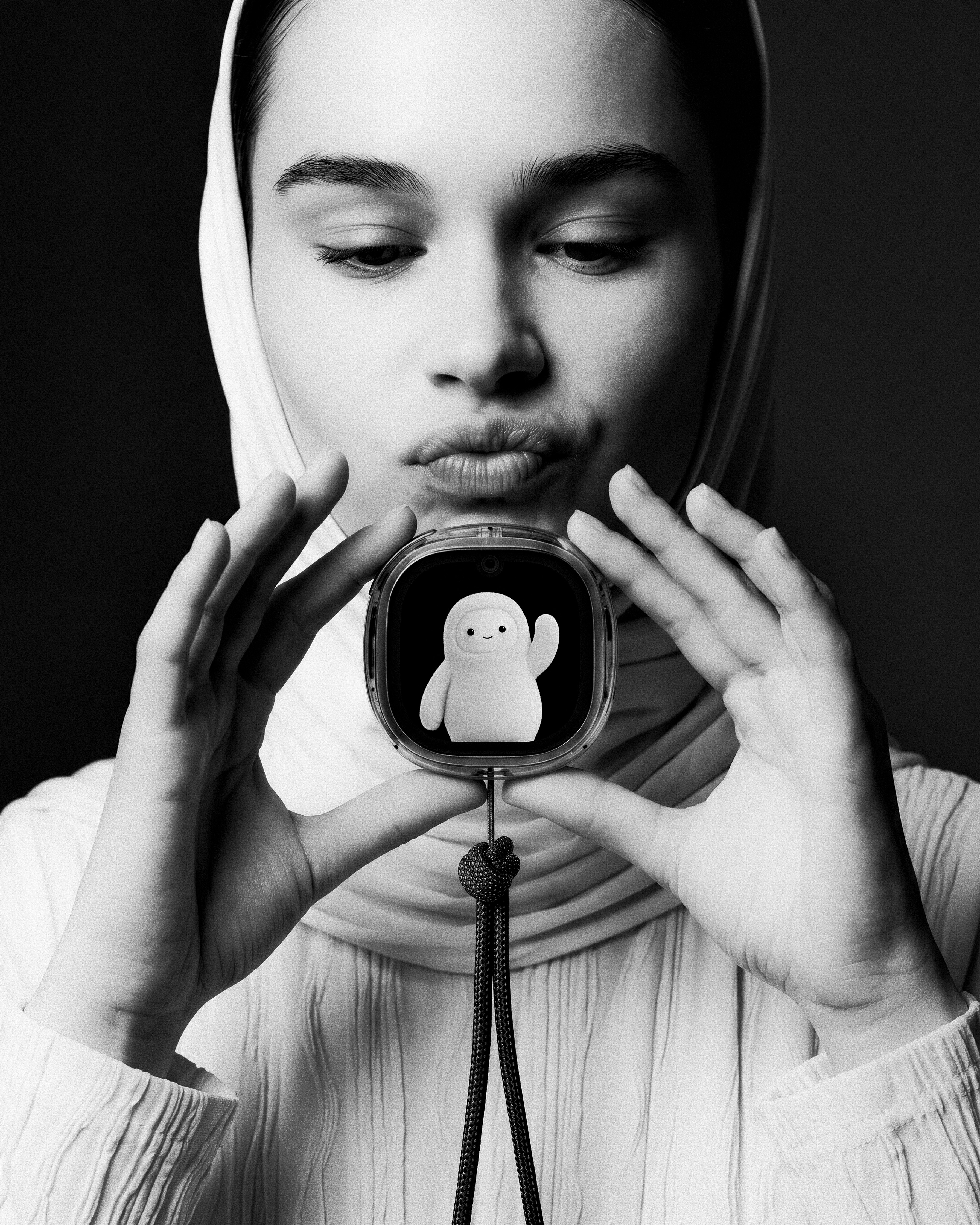 Black-and-white portrait with Muse Charm held near collar, lanyard hanging down.