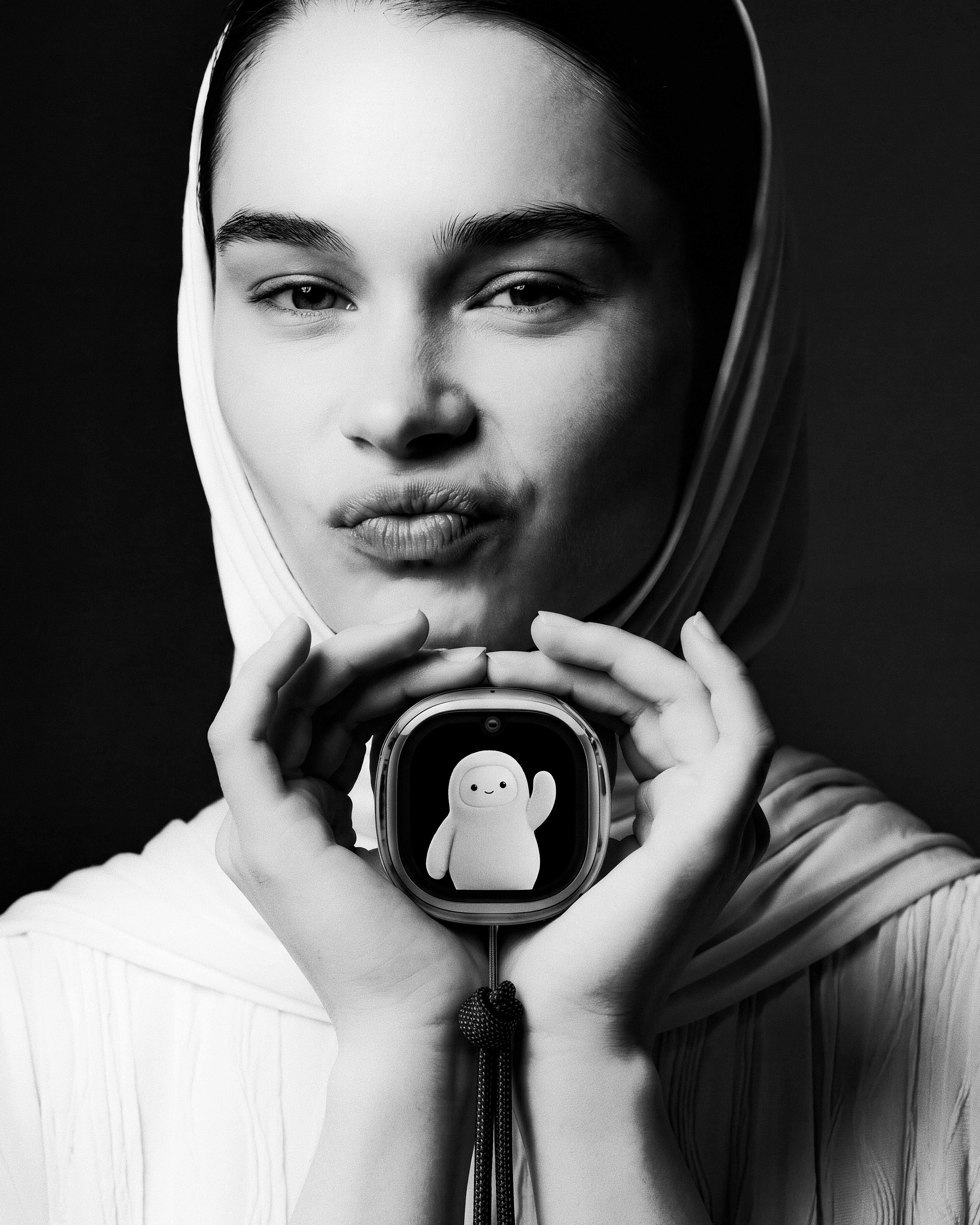 Black-and-white editorial portrait with model holding the Charm in contemplation.
