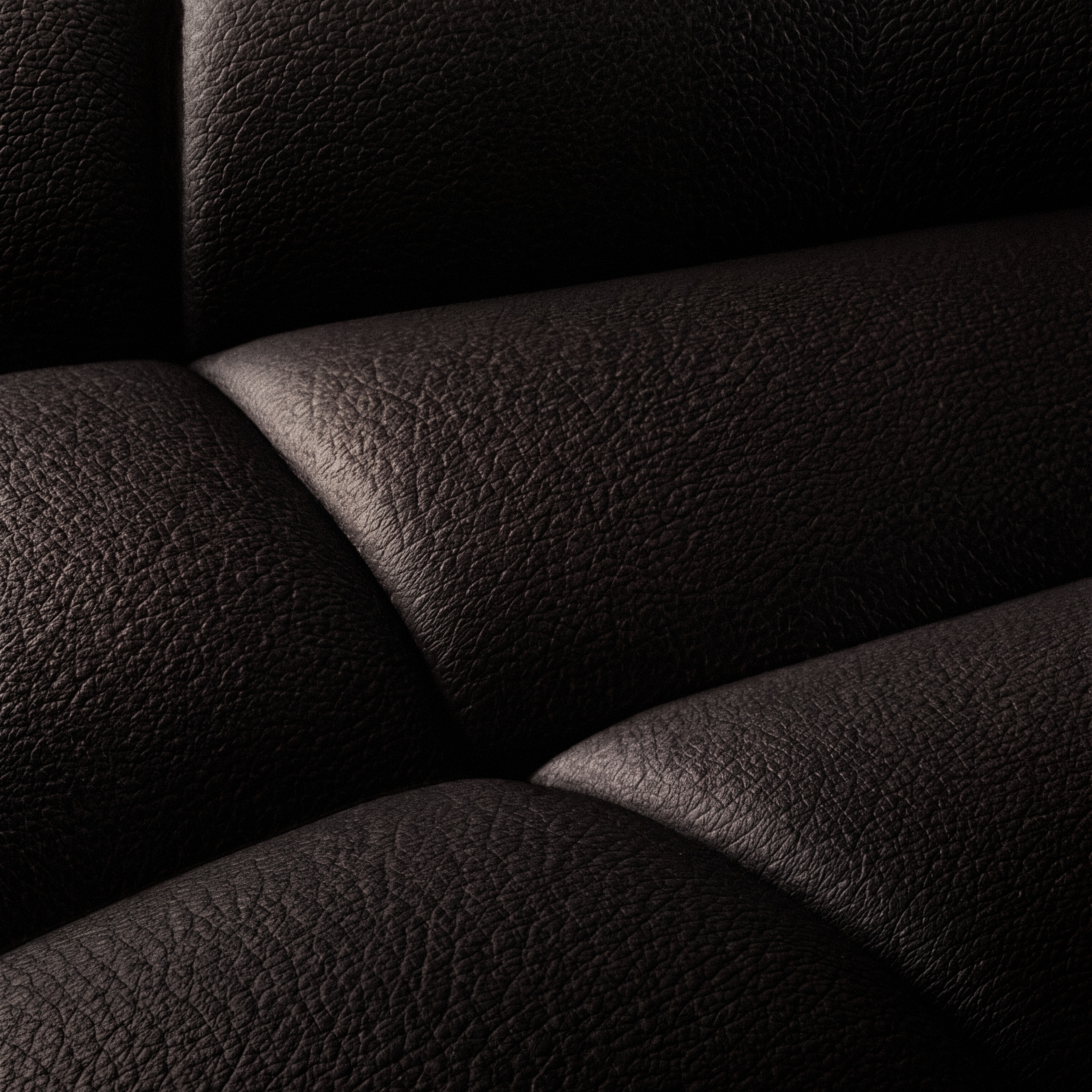 Godland · Caldera — macro detail of radial-quilted pebble-grain leather upholstery.