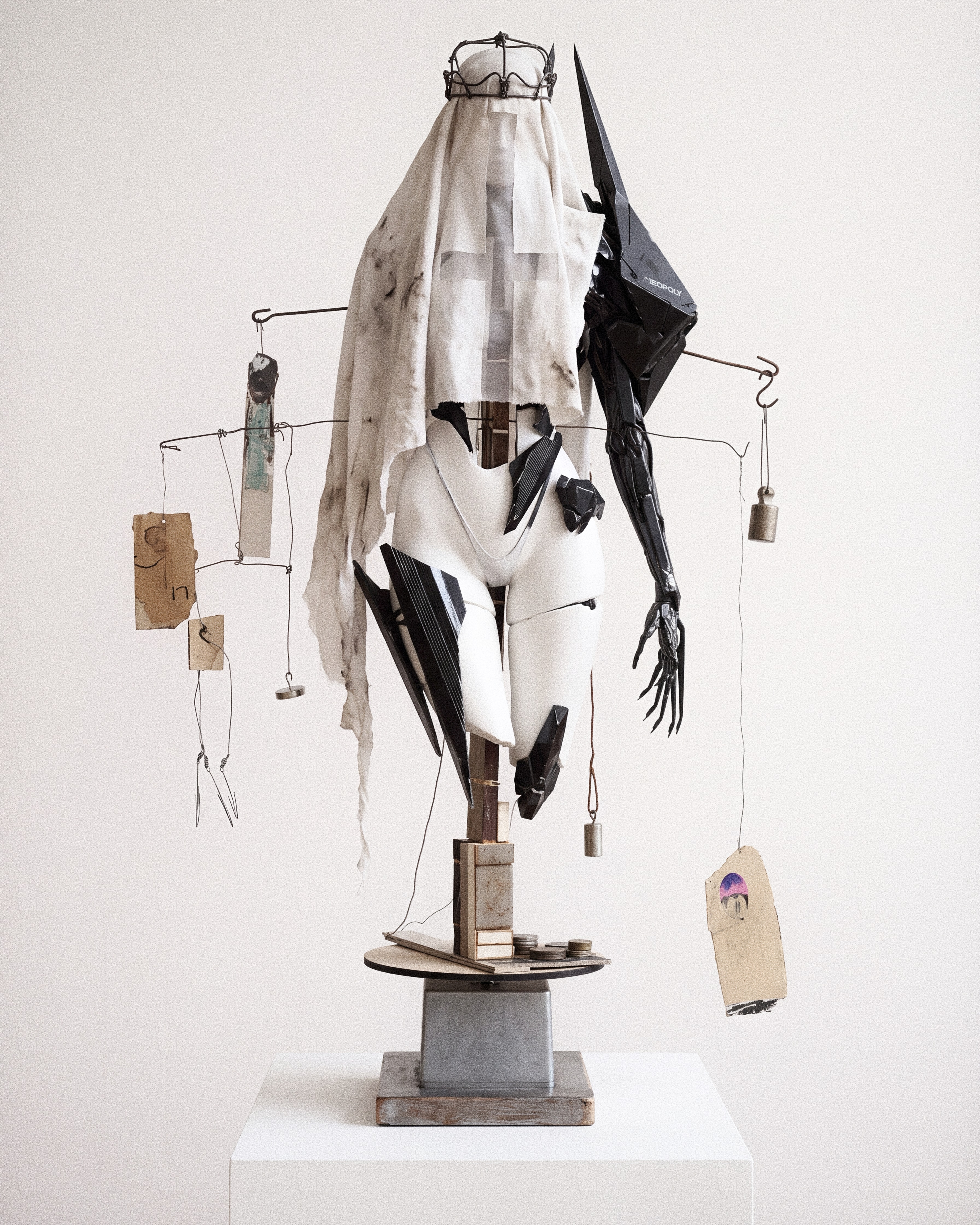 Confession Turk Plate 03 — votive reliquary sculpture on a steel plinth with shrouded torso, mechanical black arm, brass counterweights and cardboard tags.